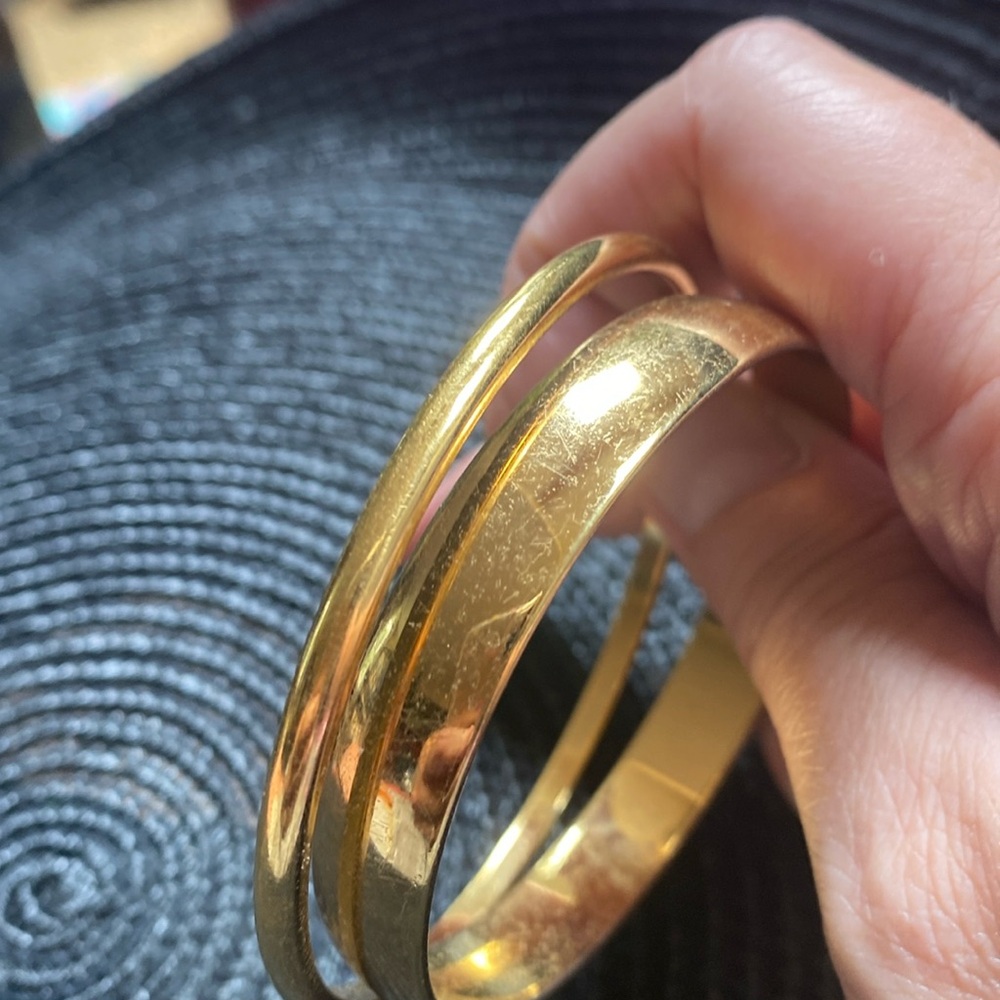Two gold tone bangles. One marked Monet